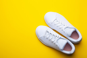Pair of casual shoes on yellow background. Top view of stylish sneakers on color background with place for text