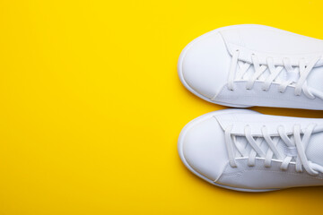 Pair of casual shoes on yellow background. Top view of stylish sneakers on color background with place for text