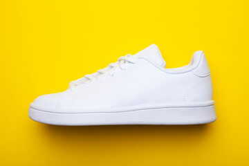 Casual shoes on yellow background. Top view of stylish sneakers on color background - obrazy, fototapety, plakaty