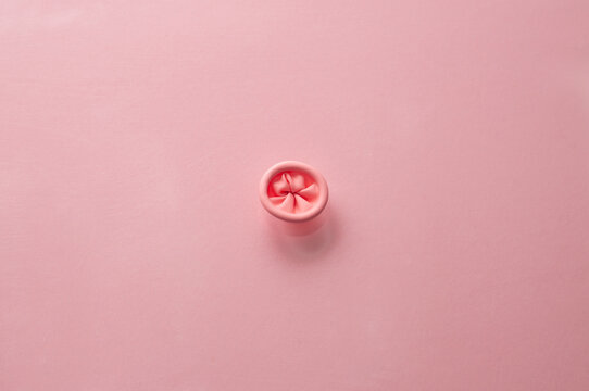 Metaphor image of the anus on a pink background. Rectal health, anus hygiene.
