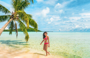 Fototapeta na wymiar Luxury beach Tahiti Bora Bora bikini woman swimming in paradise getaway vacation. Beautiful Asian swimsuit model relaxing walking in turquoise ocean water in secluded island.