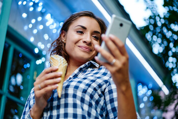 Charming Caucaisan woman with ice cream reading text publication in social networks using cellphone application during travel trip, pretty millennial browsing social media and mobile website