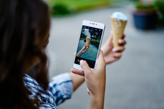 Unrecognizable female tourist clicking photo images of gelato ice cream using cellphone camera during summer vacations, selective focus on mobile screen with displayed sober dessert in scoop