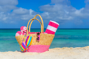 Fototapeta na wymiar Beach bag, flip flops, beach towel on the shoreline, beautiful beach