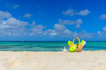 Fototapeta na wymiar Beach bag, flip flops, beach towel, star fish on the shoreline, beautiful beach