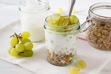 Fruit dessert. Yogurt, muesli and grapes in glass jar