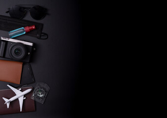 Travel concept:Top view photo of sunglasses compass camera and plane model on passport cover on dark background