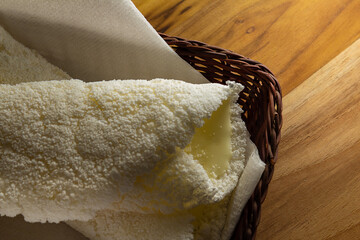 Duas tapiocas recheadas dentro de uma pequena cesta de vime sobre superfície de madeira.