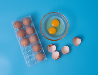 Fresh eggs in a box.Top view copy space,blue background. Broken egg with yolk