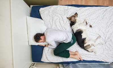 Man and dog lying on bed with blue sheet