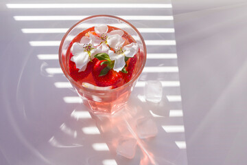 Still life with glass of cooling strawberry Sangria with sparkling wine, strawberry, ice cubes. Refreshing summer alcoholic cocktail drink , lemonade or ice tea. Copy space for text.