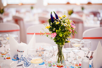 Detail of flowers on a wedding table which is ready for the guests and bride with the groom.