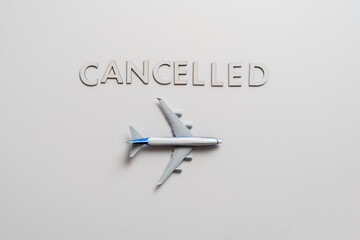 symbol of cancelled airplane flight, word "cancelled" with plane flat lay on color surface