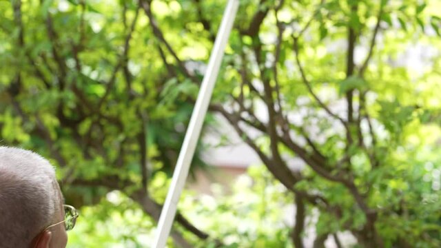 senior asian retired man use trimmer to prune tree at home