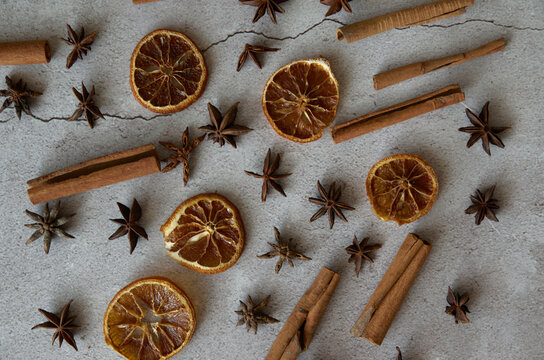 Anise seeds, aniseed pimpinella, cinnamon sticks and dried orange wedges. Laid out on a concrete background