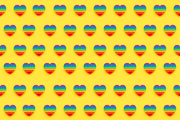 Pattern. Colorful trendy Pop it heart shape fidgets toy for kids on a yellow background.