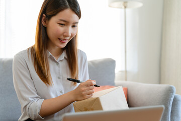 Asian woman is packing the cardboard boxes delivers to customers working from home. Female started up a small business as an online shopping