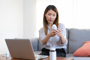 Asian female medical assistant making video call with patients for online support, Woman explaining medicine bottles working from home while coronavirus pandemic