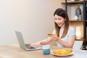 Asian woman holding a credit card typing on keyboard for online shopping or online banking