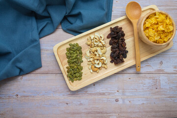 Grains in wooden tray, Currant,Cashew nut,Pumpkin seed,And Cornflakes in wooden cup on wooden floor background.