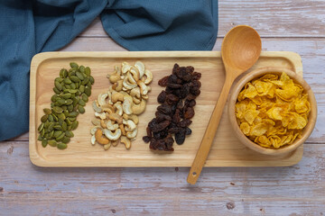 Grains in wooden tray, Currant,Cashew nut,Pumpkin seed,And Cornflakes in wooden cup on wooden floor background.