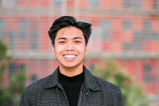 happy young asian man on city street looking at camera