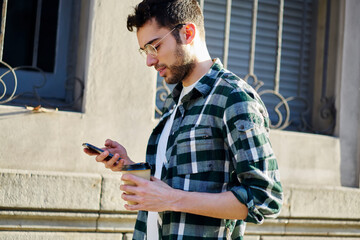 Thoughtful young man walking on street with mobile phone