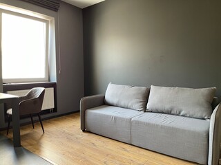 Black wall, wooden floor and grey sofa