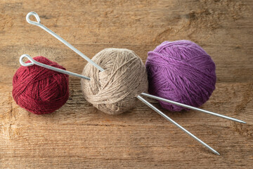 Balls of yarn in different colors with knitting needles on a background of rough wood texture