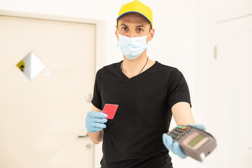 Fototapeta na wymiar Delivery man holds bank payment terminal to process acquire credit card payments. Employee in cap t-shirt working courier. Service concept