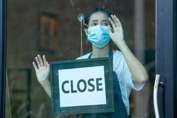 Waitress woman turning sign board to closed with wearing face mask,protection to pandemic of...