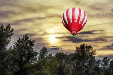 Fototapeta premium A beautiful sunrise over the forest with a hot air balloon in the sky in the early morning.