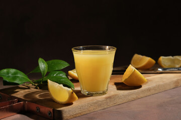 Glass of limoncello italian liqueur and fresh lemons on cutting board.