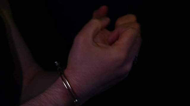 Criminal with cuffed hands in police lights
