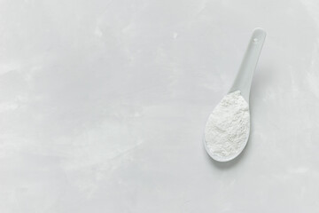 Collagen powder in a spoon on a gray concrete background with a copy space. Extra protein intake