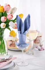 Obraz na płótnie Canvas A napkin folded in the form of hare (rabbit) ears in a glass, the concept of setting a festive table in honor of Easter.
