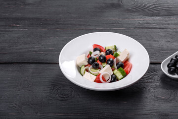 Fresh delicious Greek salad with tomato, cucumber, onions and olives with olive oil