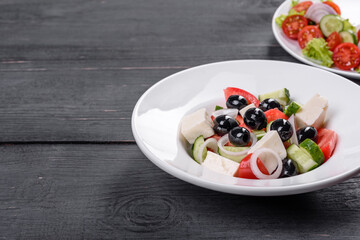 Fresh delicious Greek salad with tomato, cucumber, onions and olives with olive oil