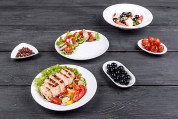 Three fresh delicious salads with chicken, tomato, cucumber, onions and greens with olive oil