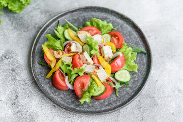 Fresh delicious salad with chicken, tomato, cucumber, onions and greens with olive oil