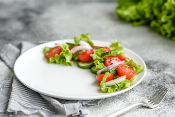 Fresh delicious salad with vegetables: tomato, cucumber, onions and greens with olive oil