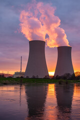 Obraz na płótnie Canvas Nuclear power plant against sky by the river at sunset