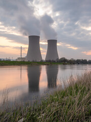Nuclear power plant against sky by the river at sunset