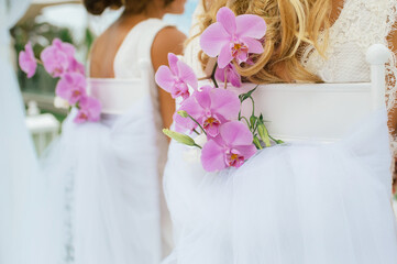 floral decoration on a chair with orchids at a gay wedding of two women. Unrecognisable person