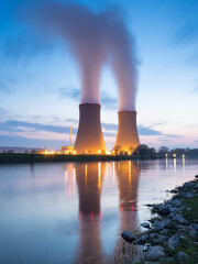 Nuclear power plant against sky by the river at sunset - obrazy, fototapety, plakaty