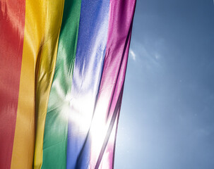 Rainbow flag in sunshine against blue sky