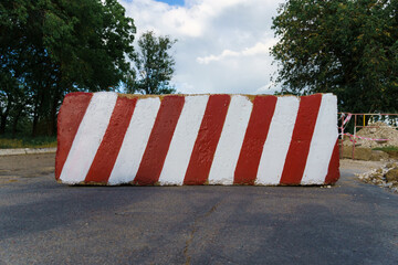 concrete block with red and white striped lines as a roadblock, traffic is prohibited and road...