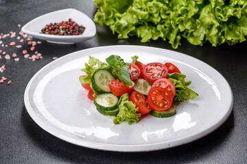 Fresh delicious salad with vegetables: tomato, cucumber, onions and greens with olive oil