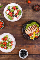 Three fresh delicious salads with chicken, tomato, cucumber, onions and greens with olive oil