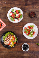 Three fresh delicious salads with chicken, tomato, cucumber, onions and greens with olive oil
